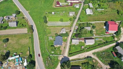 An aerial view of a plot with the house and outbuildings of a European villager. Personal subsidiary farm. Dacha. A summer house in the middle of green spaces in summer.