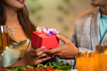 Close up shot, Boyfriend giving surprise gift to girlfriend during candle light dinner - concept of...