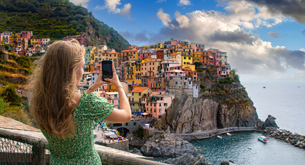 .A tourist girl taking a picture of Manarola, Liguria, Italy