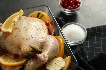 Chicken with orange slices, rosemary and berries on grey table