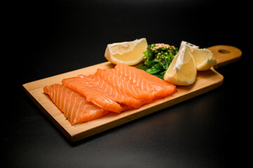 Salmon sashimi pieces with lemon and herbs presented on a dish