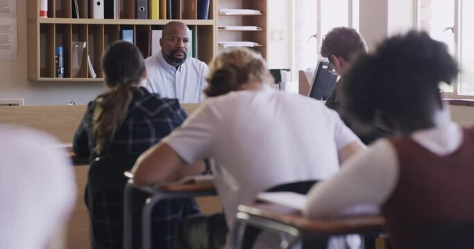 High school kids, classroom and test with teacher, man and writing for assessment, development and studying. People, students and exam for education, knowledge and back at desk in class at academy