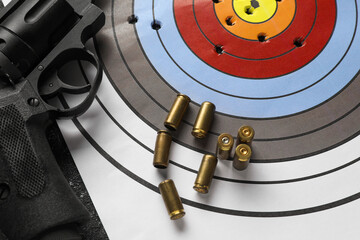Shooting target, handgun and bullets on table, top view