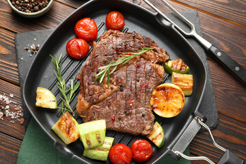 Delicious grilled beef steak and vegetables served on wooden table, top view
