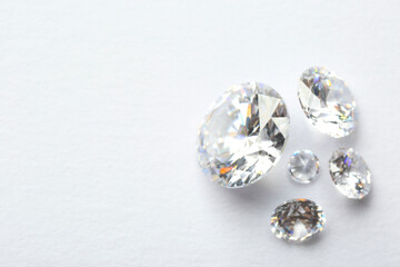 Many beautiful shiny diamonds on white background, flat lay. Space for text