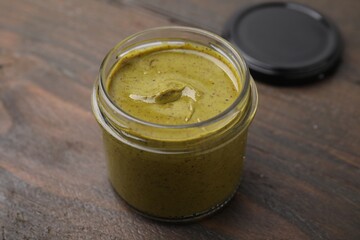 Tasty pistachio cream in jar on wooden table, closeup