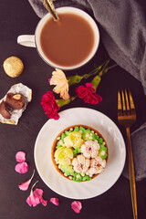 Close up of floral french tart among flowers and coffee cup. Aesthetic pink floral cake. Desserts using the trend Dreamy Escapism.