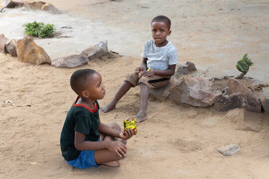 african children hanging in front of the house eating snacks and biscuits ,waiting for her mother
