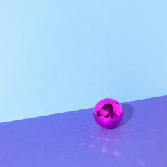 Shiny pink disco ball on table. Background with space for text.