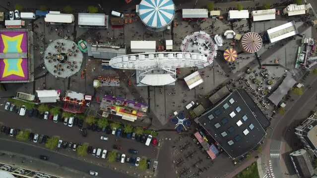 High altitude aerial view of fair showing funfair attractions like ferris wheel and wave swinger is amusement ride that is a variation on the carousel in which the seats are suspended from rotating 4k