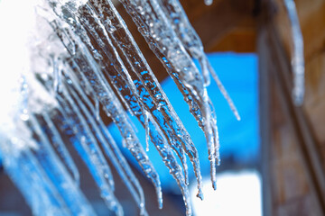 Icicle against light blue sky. Drop of melted snow falls down. Closeup. Illustration about end of...