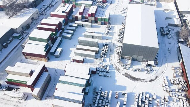 Shipping container and cargo crane at storage yard at winter time aerial view