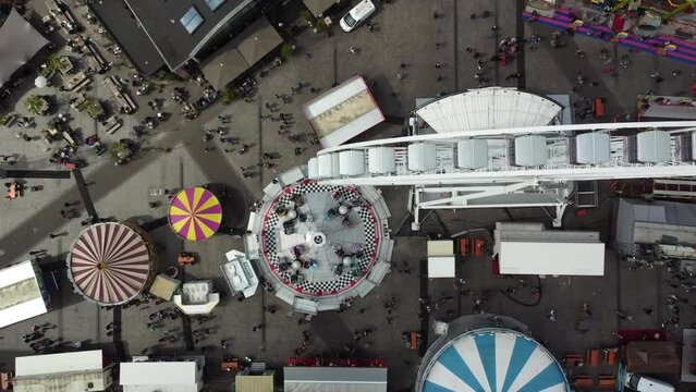 Aerial top down view of fair showing several funfair attractions like ferris wheel and wave swinger is amusement ride that is a variation on the carousel in which the seats are suspended from rotating
