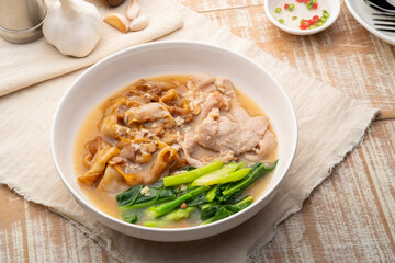 Flat Noodles with Marinated Pork and Collard greens in Gravy Sauce in white plate