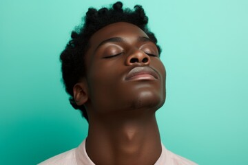 An African American man with his eyes closed on a mint background. Portrait of a sleeping male person. Self-development, hypnosis and the study of the inner world.