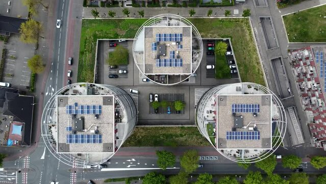 Aerial top down drone view of three modern apartment buildings located in Hilversum the Netherlands showing the real estate property roofs and solar panels streets with traffic around the complex 4k