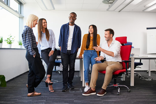 Diverse group of colleagues chatting at office work having casual conversation