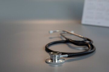 Black stethoscope and calendar on gray background, health concept