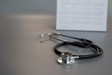 Black stethoscope and calendar on gray background, health concept