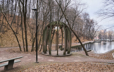 small beautiful pond in a city park with wild ducks in autumn in cloudy weather