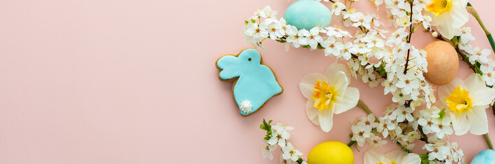 Festive banner with spring flowers and naturally colored eggs and Easter bunnies, white daffodils and cherry blossom branches on a pink pastel background - obrazy, fototapety, plakaty