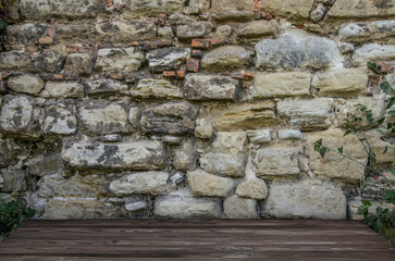 Stone brick walls and wooden floor for mock up. Rustic old wooden planks, shelf or table surface. Empty room background for product displaing and copy space for text