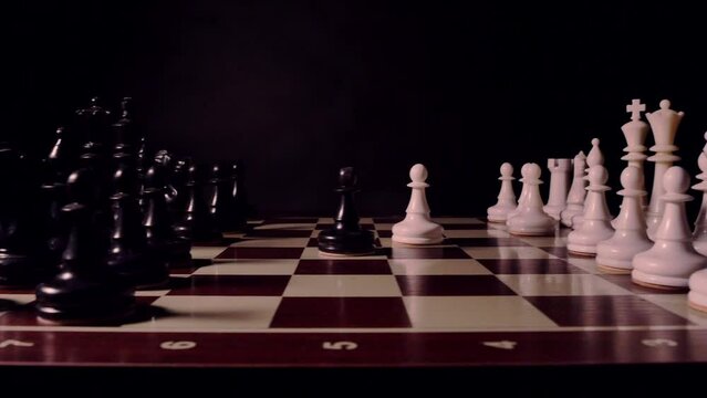 Short clip of chessboard with white and black chess pieces on black background