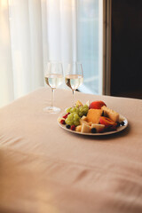 Gray sofa with two glasses of white wine and fresh fruit on the dish indoors