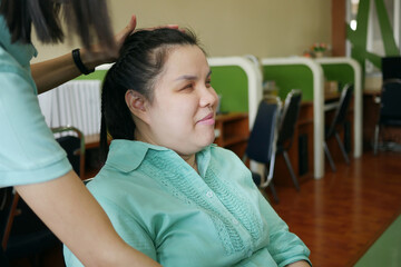 Asian woman a person with blindness disability smiling with happiness when her friend is doing hair arrangement making braids hairstyles for her in office workplace.