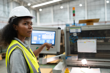 African American businesswoman working with use monitor control machine at Kraft paper factory
