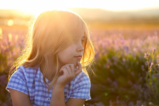 Happy little girl blonde with long hair at sunset in lavender field