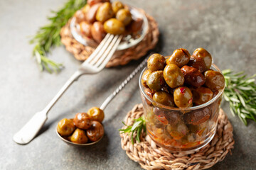 Spicy olives in a glass bowl on a stone table.