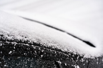 pare-brise, capot et porte de voiture noire sous la neige, en gros plan