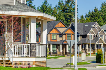 Neighbourhood of luxury houses with street road, big trees and nice landscape in Vancouver, Canada. Blue sky.