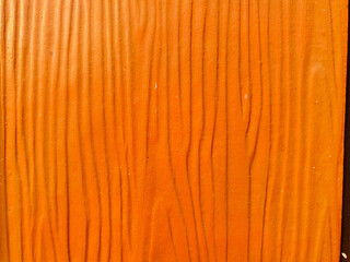 Vibrant orange wood grain texture background. A close-up of a faux wood panel with vertical lines, creating an abstract pattern for design and architectural concepts.