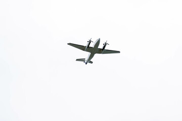 Silhouette of a twin-engine plane flying in a blue sky between clouds. Transportation. Aircraft.