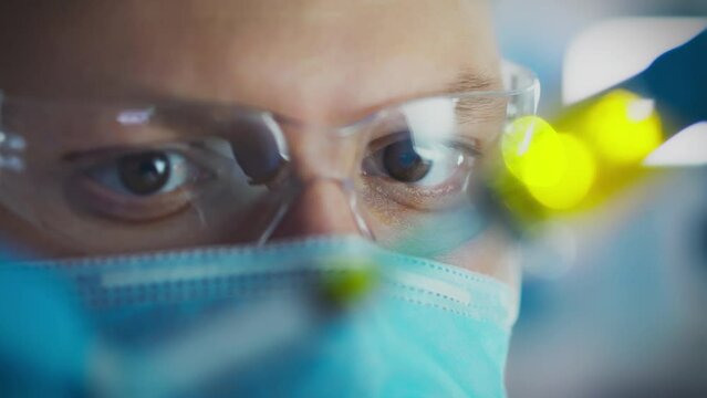 Close-up of a laboratory worker's eyes. The doctor of scientific works carefully looks at the medicine for suitability. Eyes in glasses close-up of a worker at a scientific research complex