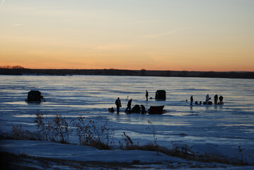 A cluster of ice anglers at sunset