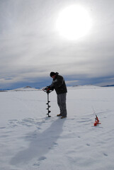 Fototapeta na wymiar Ice fisherman drilling a hole