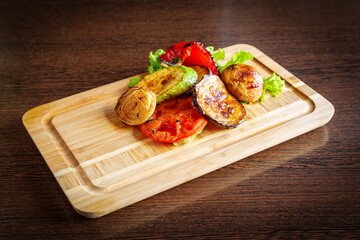 Grilled vegetables: onion, tomato, zucchini, grilled eggplant and lettuce on a wooden board.