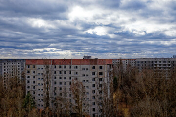 A gloomy day with clouds hovering over aged apartment complexes surrounded by leafless trees.