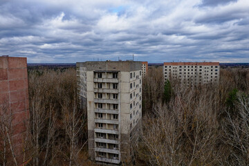 Fototapeta na wymiar Deserted residential towers overshadowed by thriving natural growth.