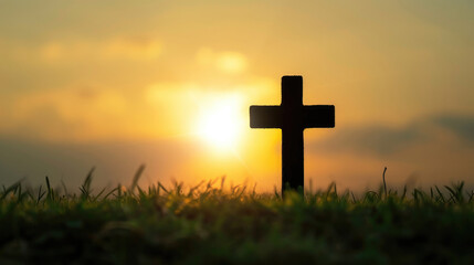 Silhouette cross at sunrise on grass.