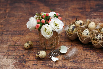 Fototapeta na wymiar Frohe Ostern Grußkarte: Wachteleier mit Blumestrauß auf einem Holztisch mit Platz für Text.