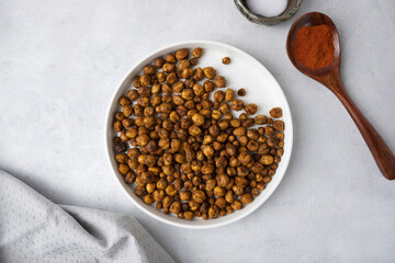 Roasted chickpeas with smoked paprika and salt on a light background in a white plate. View from above. Healthy seasoned chickpeas with various spices