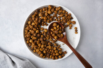 Roasted chickpeas with smoked paprika and salt on a light background in a white plate. View from above. Healthy seasoned chickpeas with various spices