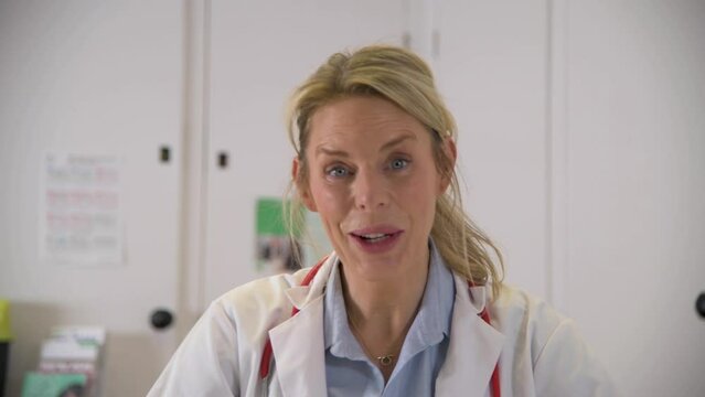 A blond, female doctor in blue scrubs consults a virtual patient over laptop, he discusses symptoms and then prescribes medicine. 
