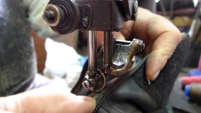 Repair of old shoes at a craftsman specialized in repairing all types of shoes. Close-up of repairing old leather shoes, detail of needle on old zipper stitching machine