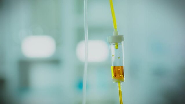 The infusion of medicinal liquid into the IV drip is done in close-up as the saline solution drips from the bag. Transparent tubes effectively guide fluid through the infusion system