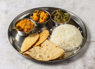 Vegetable thali set with plain rice, palak, dal, mixed vegetable of aloo gobi matar, palak, shorba and chapati served in dish isolated on background top view of indian spicy food